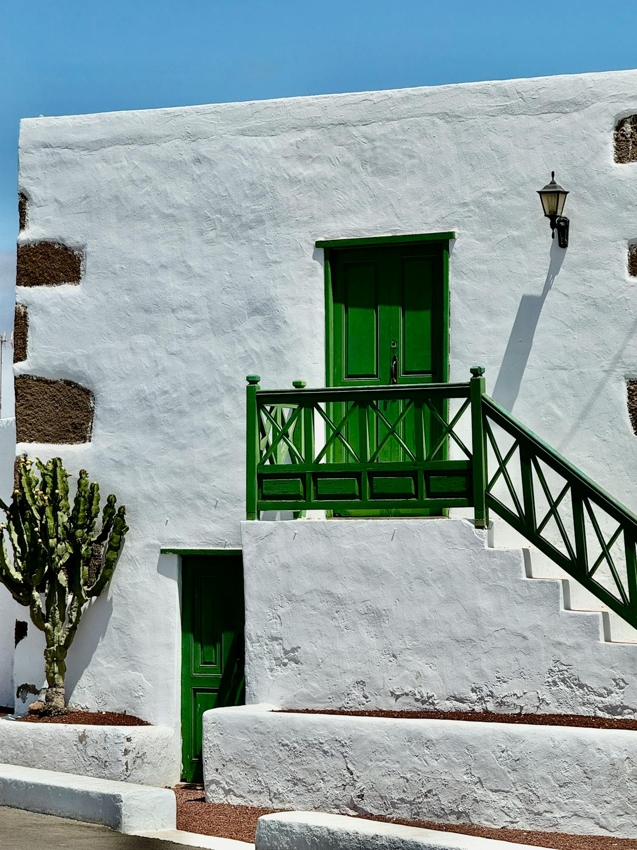 Whitewashed Canarian building with vibrant green doors — the Art-Nature palette of Lanzarote
